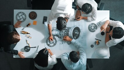 Top down aerial view of smart engineer team working together to design turbine engine. Professional...