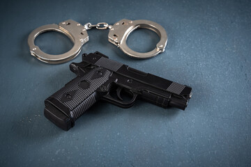 Gun and handcuffs on blue background, stock photo, criminal concept