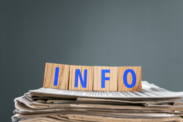 Newspapers on wooden cubes with "INFO" written on them, studio background, stock photo
