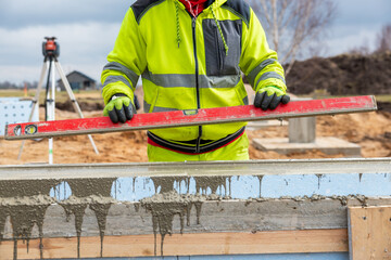 Construction Worker Using Level on Insulated Concrete Forms at Building Site