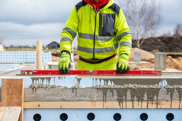 Construction Worker Using Level on Insulated Concrete Forms at Building Site