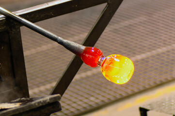 glass blowing  by  man blowers working the craft of making glassware by blowing air inside - 770022202
