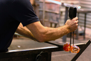 glass blowing  by  man blowers working the craft of making glassware by blowing air inside - 770022205