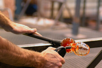 glass blowing  by  man blowers working the craft of making glassware by blowing air inside - 770022206
