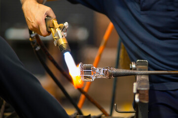 glass blowing  by  man blowers working the craft of making glassware by blowing air inside - 770022229