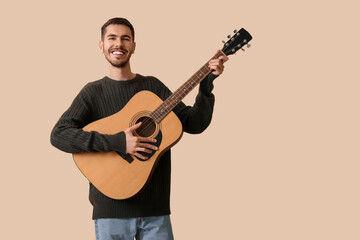 Naklejka premium Handsome young man playing guitar on beige background