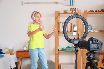 Teenage blogger with headphones recording video at home
