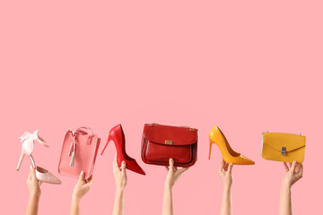 Female hands with stylish women's bags and high heels on pink background