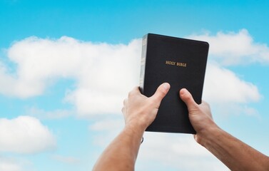 Human Praying with bible book on sky background