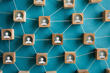 Wooden cubes with the image of person are connected with thread. Team interaction and personnel management concept