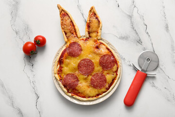 Plate with tasty pizza, tomatoes and cutter on white marble background. Easter celebration