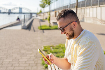man using mobile phone text messaging on the street. Hipster guy shopping online. Man holding...