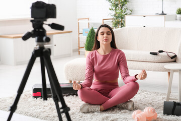Female sports blogger meditating while recording video at home