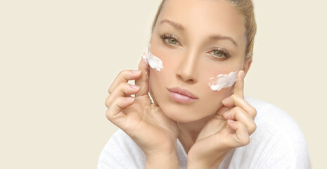 woman applying serum, lotion to her face