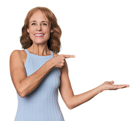Redhead mid-aged Caucasian woman in studio excited holding a copy space on palm.