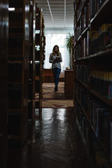 Young attractive woman standing in library	