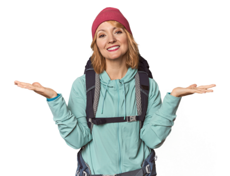 Middle-aged Caucasian woman with hiking gear makes scale with arms, feels happy and confident.