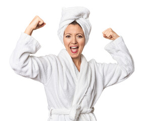 Caucasian woman in bathrobe and towel showing strength gesture with arms, symbol of feminine power