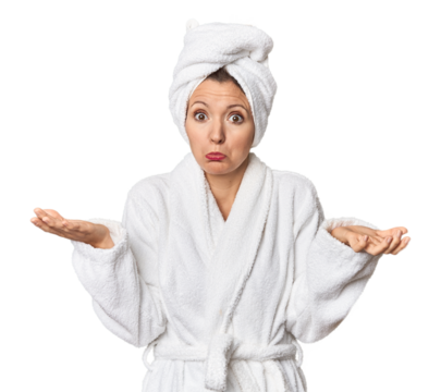 Caucasian woman in bathrobe and towel doubting and shrugging shoulders in questioning gesture.