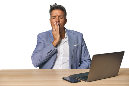 Elegant businessman at desk with laptop yawning showing a tired gesture covering mouth with hand. - Powered by Adobe