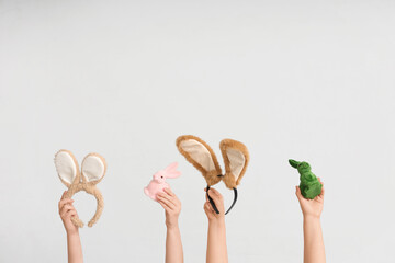 Female hands holding Easter bunny ears headbands and toy rabbits on white background