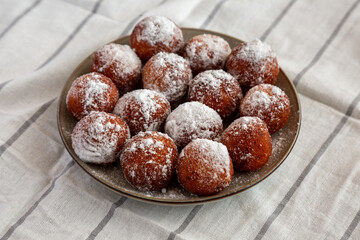 Homemade Fried Donut Holes with Powdered Sugar on a Plate, side view.