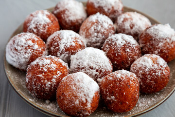Homemade Fried Donut Holes with Powdered Sugar on a Plate, side view. Close-up.