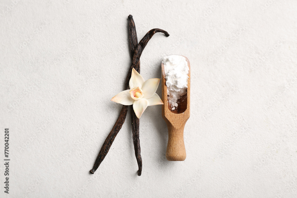 Wall mural Wooden scoop with vanilla powder, sticks and flower on light background