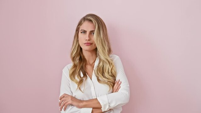 Attractive young blonde, doubt over her face. she's crossed her arms disapprovingly, standing against a pink wall, enveloping negative vibes. an angry skeptic isn't exactly miss popularity!