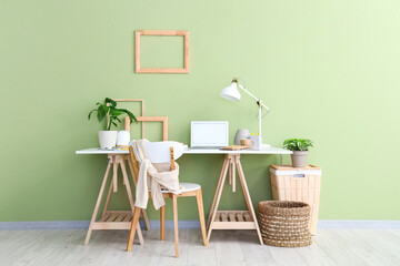 Workplace with lamp, houseplant and laptop in light office