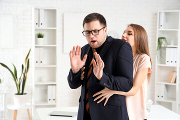 Business woman seducing her male colleague in office. Harassment concept - obrazy, fototapety, plakaty