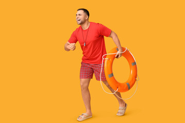 Happy young lifeguard with lifebuoy running on yellow background