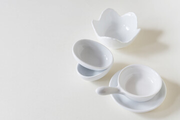 Small, white porcelain dishes on a light background.