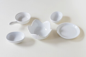 Small, white porcelain dishes on a light background.