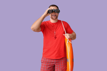 Happy young lifeguard with lifebuoy and binoculars on lilac background