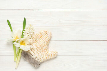 Massage glove and flowers on light wooden background