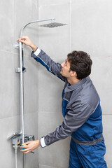 Handsome plumber fixing shower in the bathroom