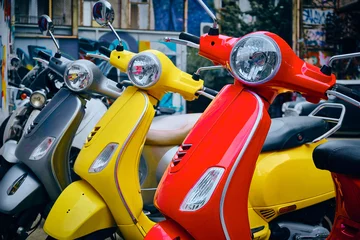 Tuinposter Vintage red, yellow and grey scooter parked in a row. Three bright colorful scooters on a parking © Philipp Berezhnoy