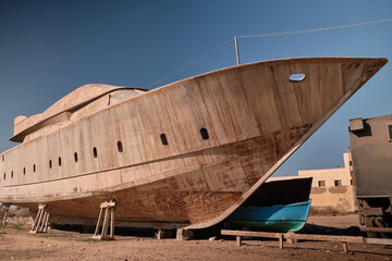 Craft shipyard. Hull of yacht at wharf under construction. Low angle view of yacht frame on a...