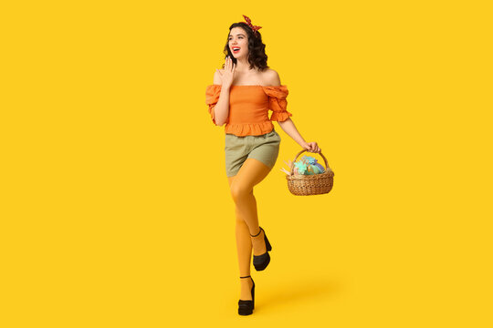 Beautiful pin-up woman with Easter basket on yellow background