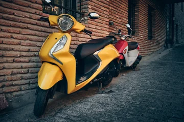Tuinposter Vintage yellow and red scooter parked by the building © Philipp Berezhnoy