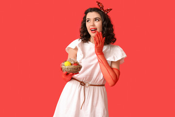 Emotional pin-up woman in laced gloves holding Easter eggs on red background