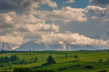 Spring green mountain landscape with meadows and rocky peaks. Landscape with a chapel and...