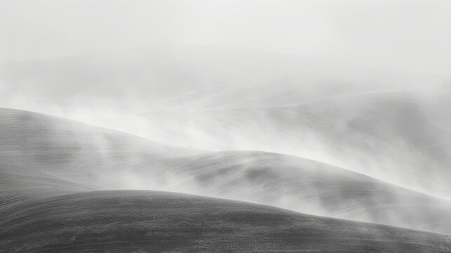  A monochrome image of a rolling landscape featuring hilly terrain in the background and foggy foreground