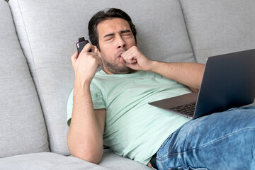 Young man using disposable electronic cigarette during work on laptop at home. Vape smoking concept	