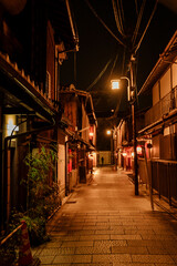 Fototapeta na wymiar A lone figure walks through a lantern-lit alley in Kyoto, Japan, embodying the solitude of night.