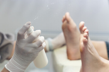 Pedicurist spraying disinfectant on client's feet