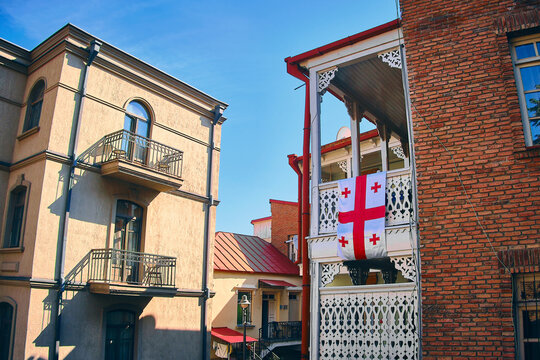Georgian flag hangs on wooden ornate balcony at Old town of Tbilisi, Georgia
