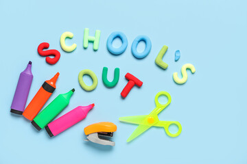 Text SCHOOL'S OUT, colorful markers and scissors on blue background. Top view