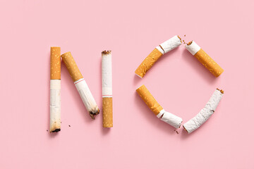 Word NO made of cigarette butts on pink background, closeup. Stop smoking concept.